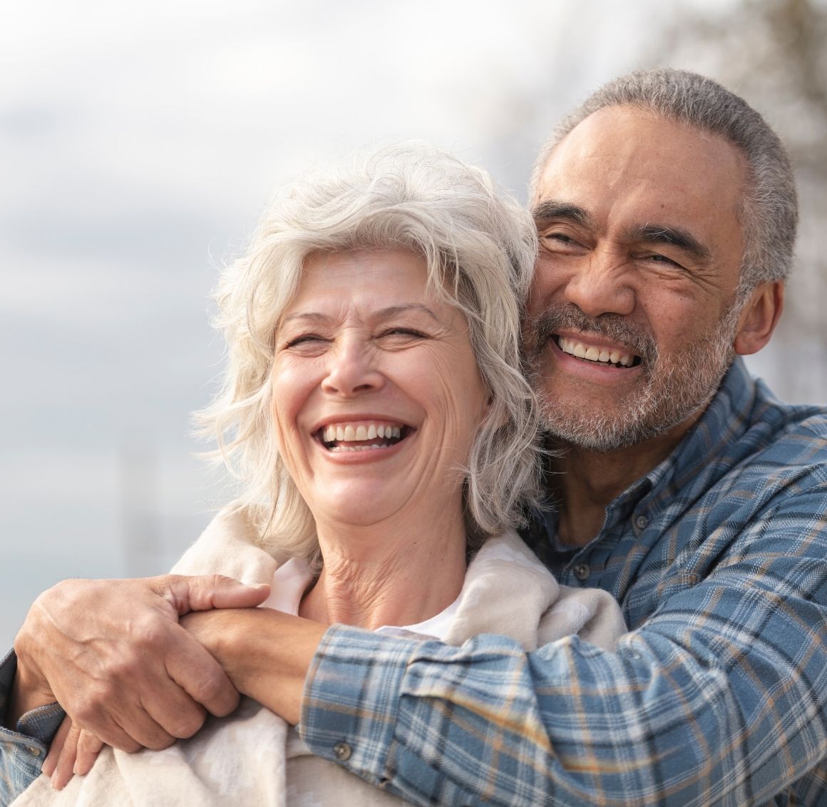 Smiling elderly couple sitting closely together, enjoying a warm moment at home.