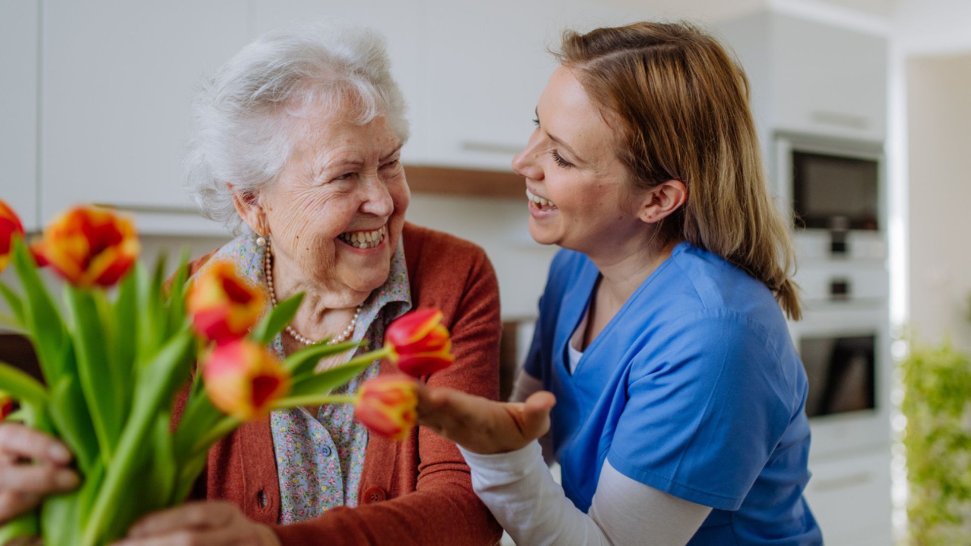Caregiver smiling and talking with an elderly woman during home care in Bloomington, MN